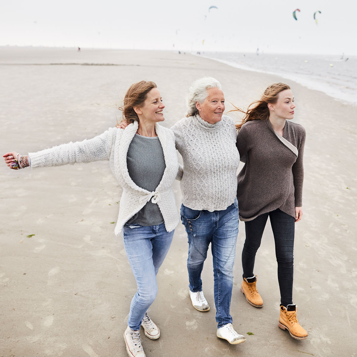 Drei Frauen gehen Arm in Arm am Strand