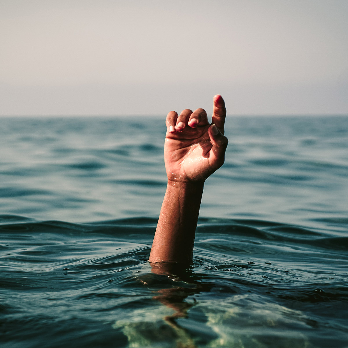 Ozean mit Hand, die aus dem Wasser reckt