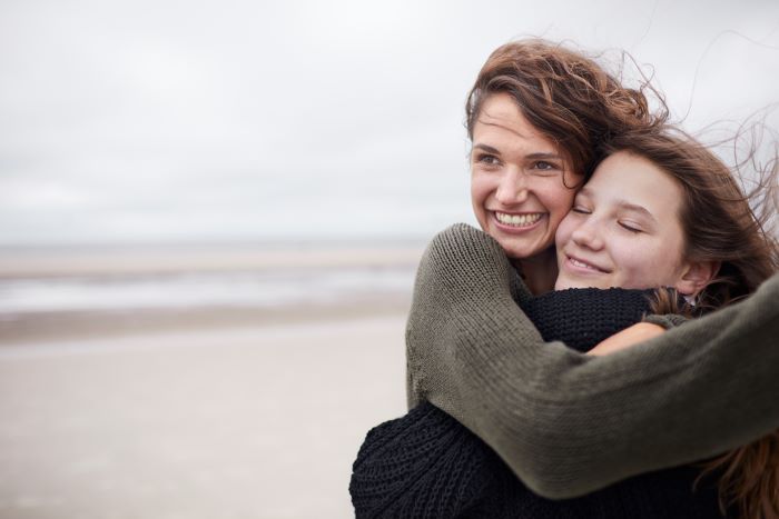 Zwei Frauen am Strand umarmen sich