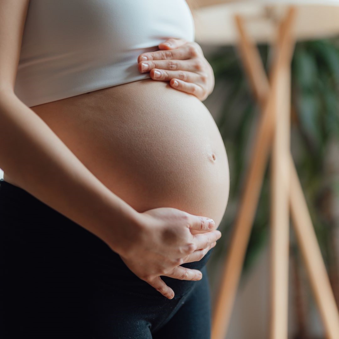 Schwangere Frau hält sich den Bauch