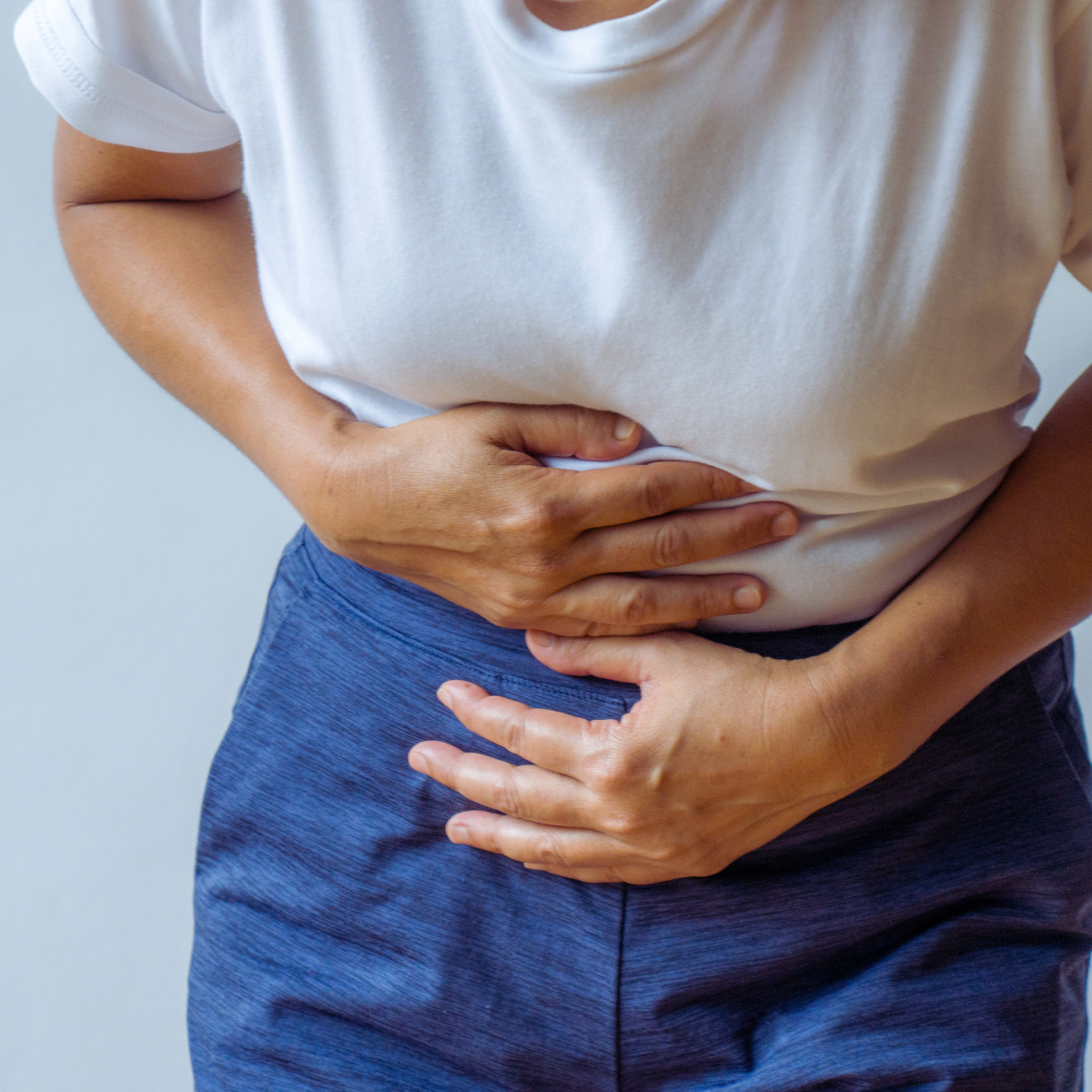 Frau hält sich vor Schmerzen gekrümmt den Bauch